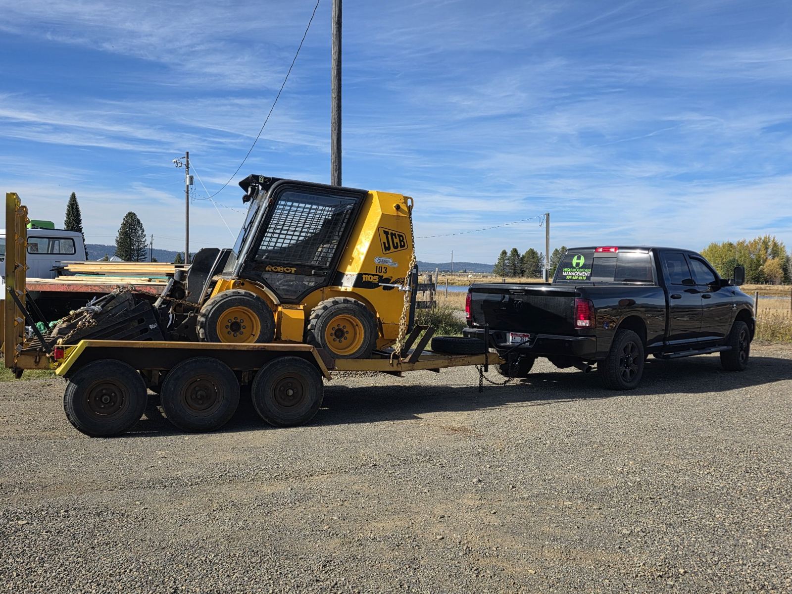 High Mountain Management truck towing a JCB skidsteer on a trailer